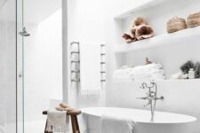59 an airy neutral bathroom with a skylight, a shower space, an oval tub, a niche with shelves for decor and storage and a boho rug