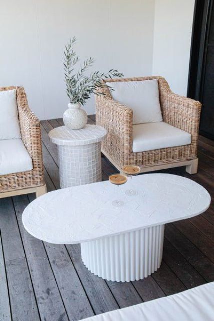 a small and cool terrace with wicker chairs, a side table and a fluted coffee table looks ethereal and trendy