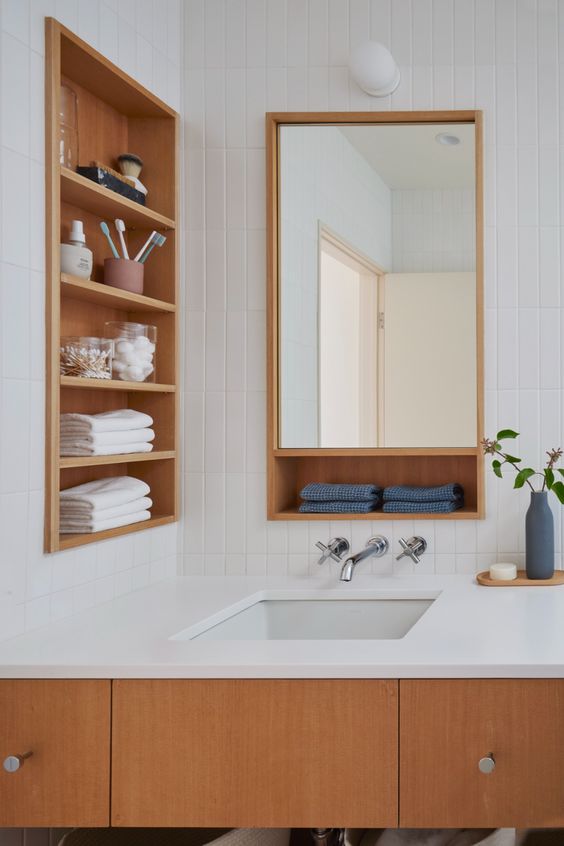 a modern farmhouse bathroom done with white tiles, with a stained vanity, a timber niche with shelves for storing some stuff
