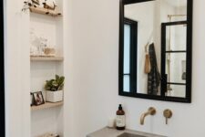 75 a modern neutral bathroom with a niche with shelves used for decor, a concrete wall-mounted sink, a black framed mirror