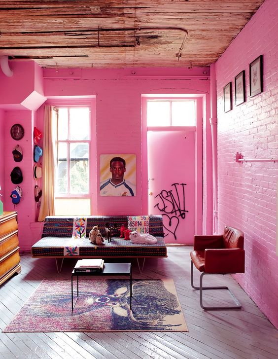 a bright pink living room with brick walls, mid-century modern furniture, bright hats and artworks