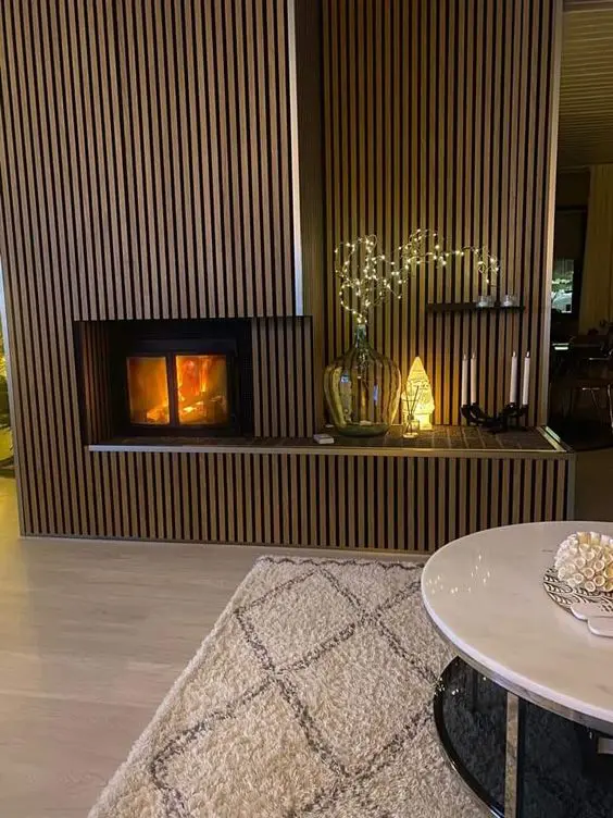 a built-in fireplace with a fluted surround and some additional decor - candles, lamps and lights next to it