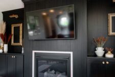 a catchy living room with a black fluted wall and a matching fireplace surround, cabinetry, lovely decor is all cool