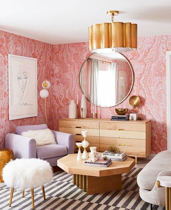 a chic living room with pink printed wallpaper, wooden furniture, a lavender chair, neutral items and touches of gold