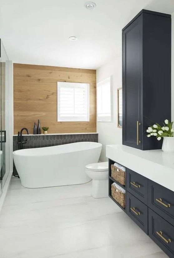 a chic modern country bathroom with a stained wood wall, a black tile accent, navy shaker style cabinets, white appliances and black fixtures