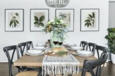 a chic modern country dining room with a stained table, black woven chairs, a wooden bead chandelier, a mini gallery wall