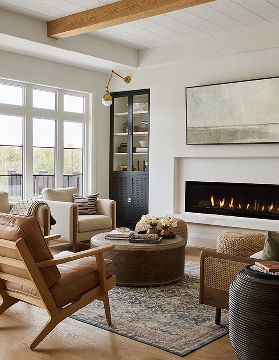 a chic modern farmhouse living room with a built-in fireplace, a built-in storage unit, neutral fabric and leather chairs, a sofa and some tables