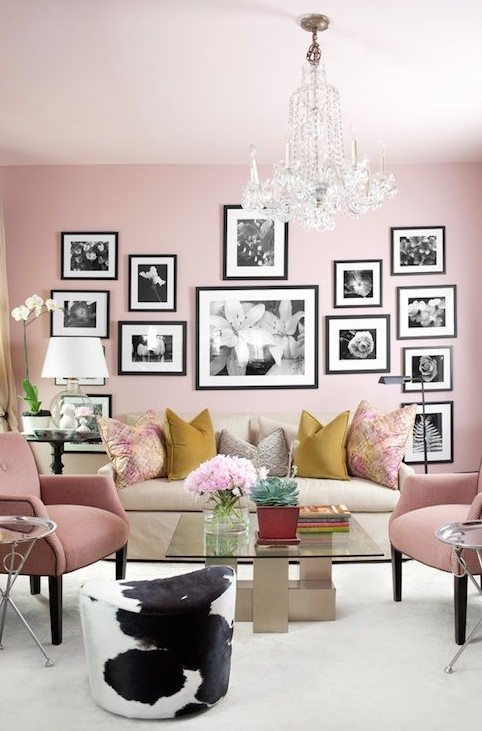 a chic pink living room with light pink chairs, a black and white gallery wall and colorful pillows