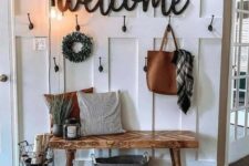 a cozy farmhouse entry with a jute rug, a wooden bench, a sign, bulbs and a wreath plus some candle lanterns