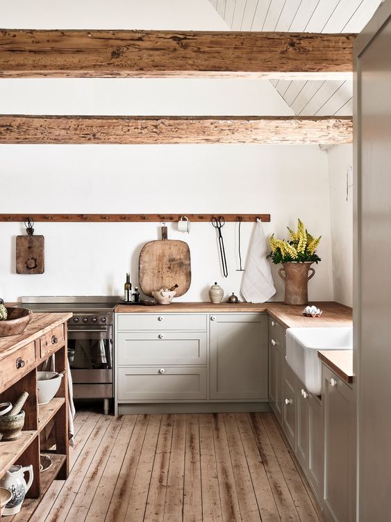 a cozy modern farmhouse kitchen with odve grey cabinets, stained countertops and wooden beams, a stained kitchen island and a stained floor