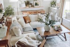 a cozy modern farmhouse living room with a console and chairs, a shelf with a mirror, a dresser, a white sectional, some tables and a leather chair