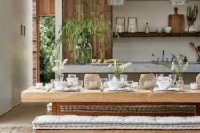 a cozy rustic dining room wiht a wooden beam, a table with a stone tabletop, wooden benches with cushions and glass pendant lamps