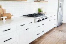 a cozy white modern farmhouse kitchen with a white subway tile backsplash, touches of natural wood and black fixtures