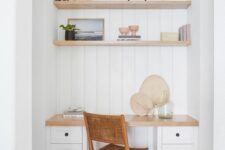 a deep white niche with shiplap, built-in shelves and a large desk with drawers, some books and decor and a cane chair