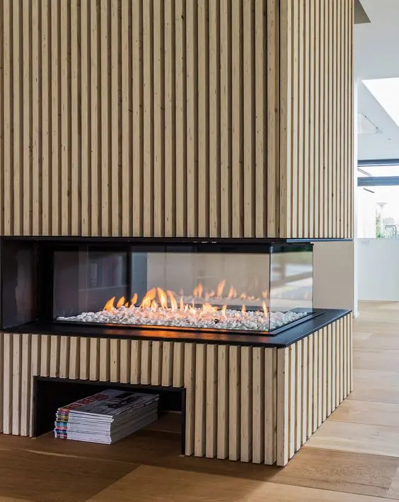 a double-sided fireplace with a reeded surround and a niche underneath for books and magazines is wow