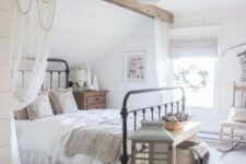 a dreamy farmhouse bedroom with a wooden beam and curtains on it, with a wooden candle lantern, some baskets and pretty bedding