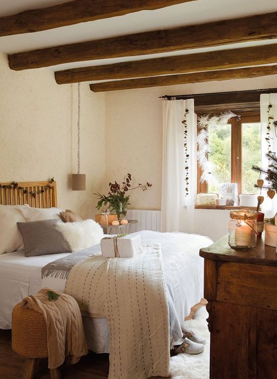 a farmhouse bedroom with wooden beams on the ceiling, wooden furniture, neutral bedding and candle lanterns is very cozy