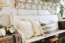 a farmhouse ebtryway with a shabby chic bench, a basket with clocks, pillows and blankets, a shelf with greenery and vintage mirrors