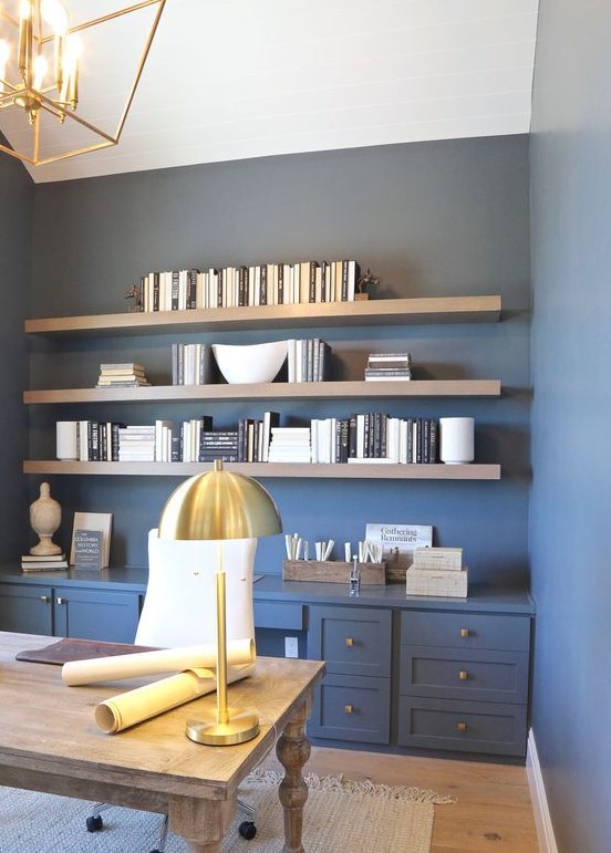 a farmhouse home office with blue walls, wooden shelves and a vintage desk, gold lamps and knobs for a touch of chic