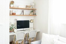 a farmhouse niche with shiplap, built-in stained shelves, a white desk, rattan chairs, decor, potted greenery and a table lamp