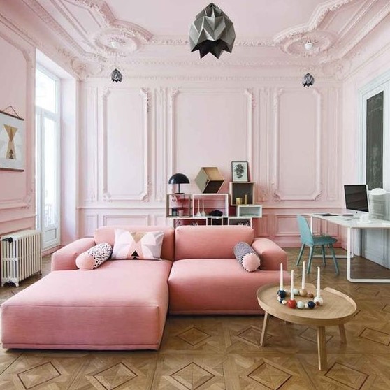 a gorgeous blush living room with molding, a pink sofa, a creative storage unit and a working space at the wall