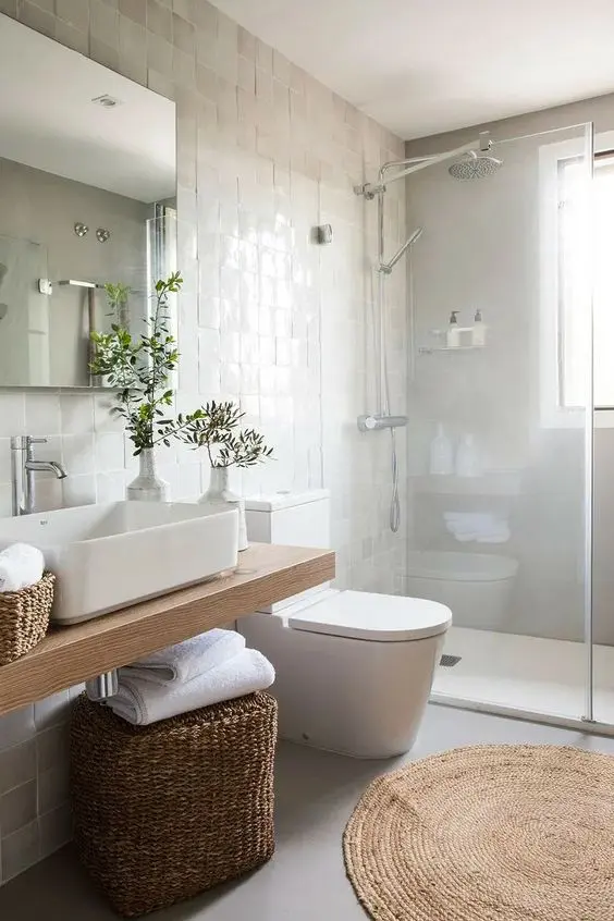 a lovely modern farmhouse bathroom with neutral Zellige tiles, a wall-mounted vanity, a jute rug, baskets for storage