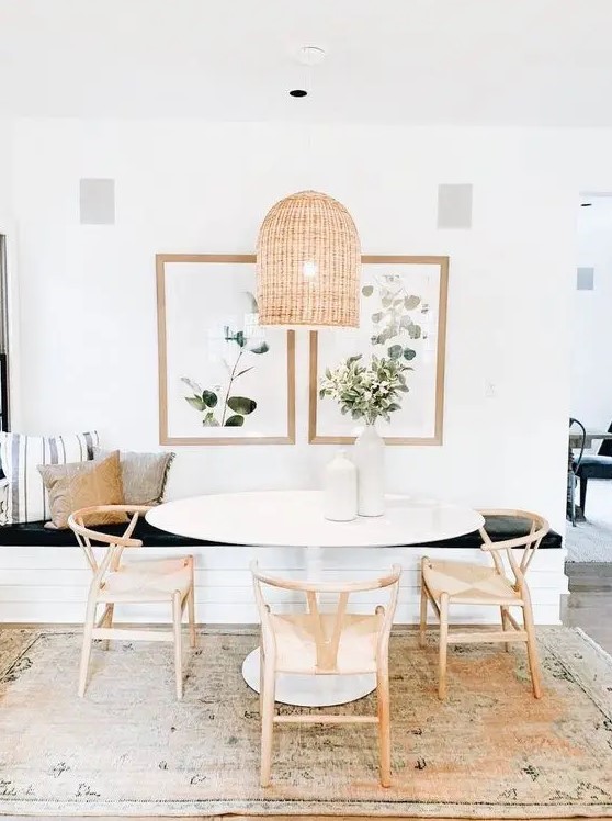 A lovely modern farmhouse dining room with a built in bench, an oval table and wooden chairs, a woven pendant lamp