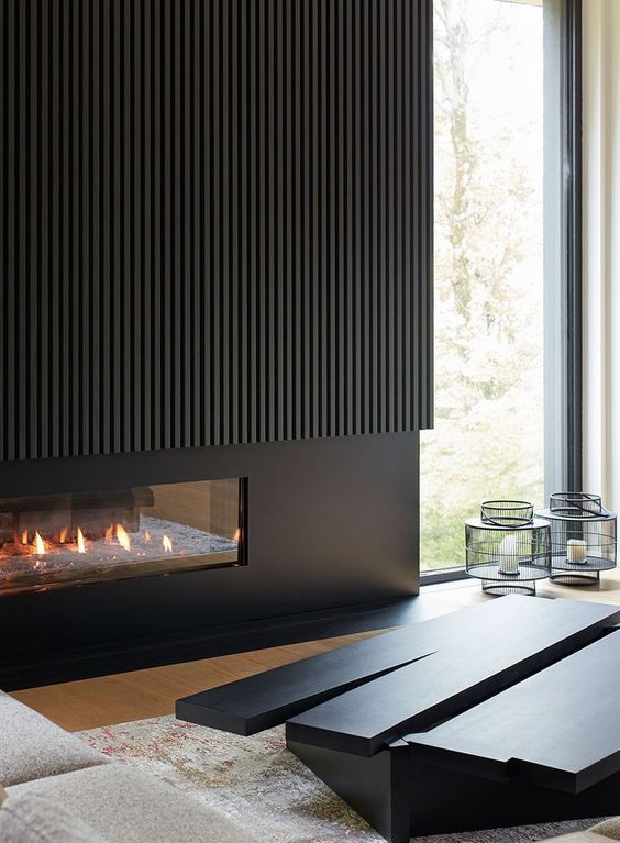 a minimalist black fireplace with a fluted surround only on top is a stylish and elegant solution for a contemporary space