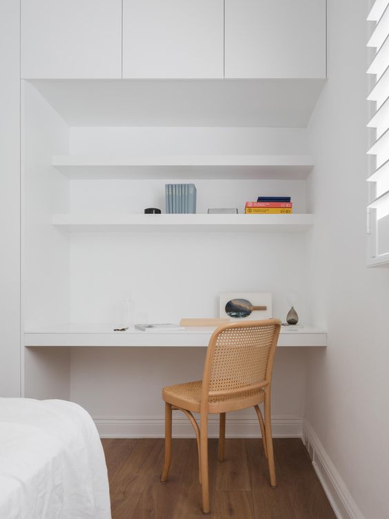 A minimalist niche with built in shelves and a desk, some books and a cane chair is a lovely nook to squeeze into a bedroom