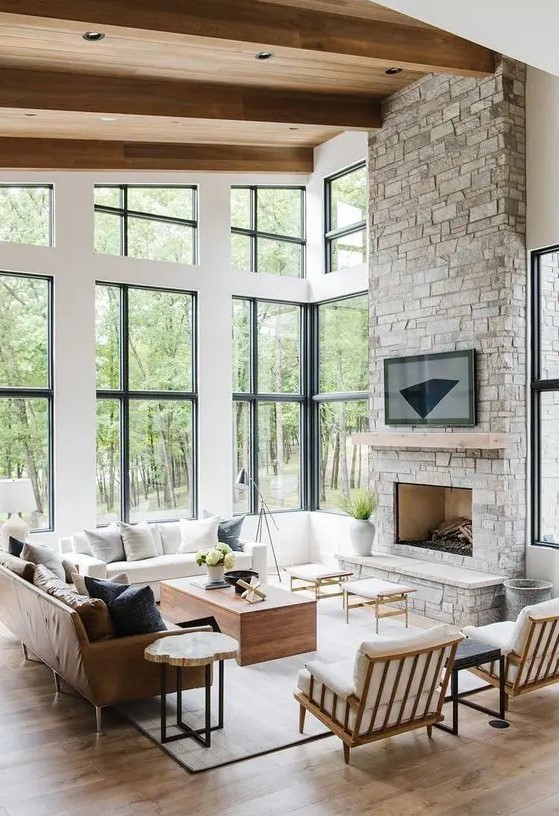 a modern Provence style living room with a fireplace clad with stone, chic neutral furniture, stools and coffee tables