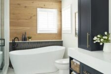 a modern farmhouse bathroom with a wood accent wall, a shower, a tub, graphite grey cabinets with a white stone countertop