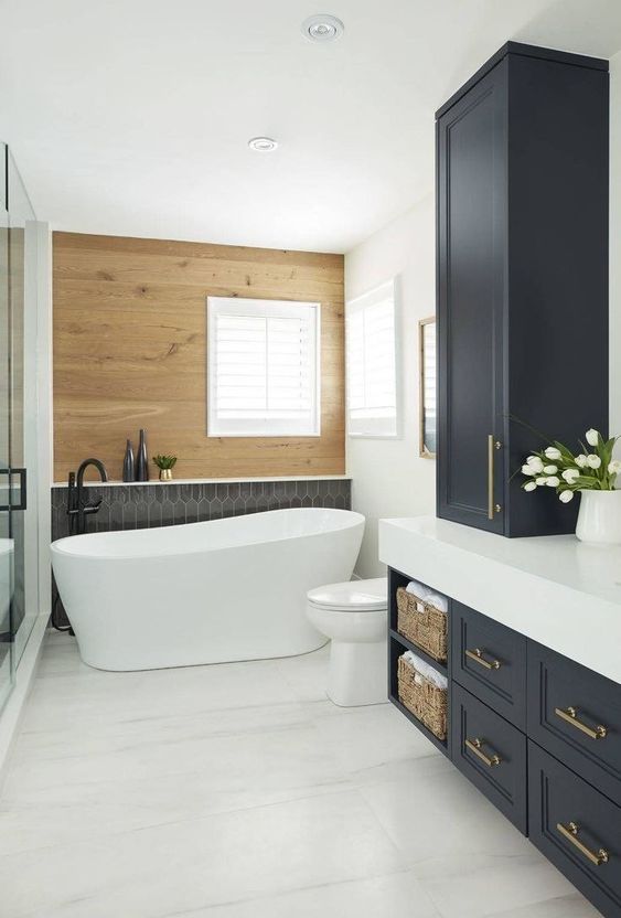 a modern farmhouse bathroom with a wood accent wall, a shower, a tub, graphite grey cabinets with a white stone countertop