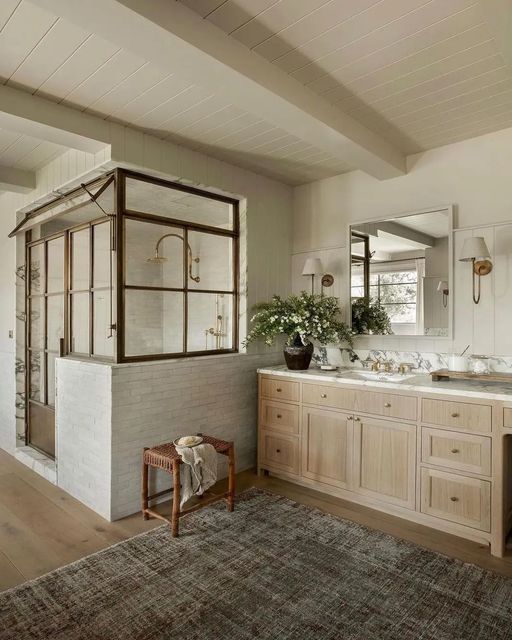 a modern farmhouse bathroom with shiplap and skinny tiles, a timber vanity, a shower space, a wooden stool and a mirror