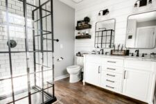 a modern farmhouse bathroom with shiplap walls and white subway tiles, a shower space, a white vanity, mirrors and shelves