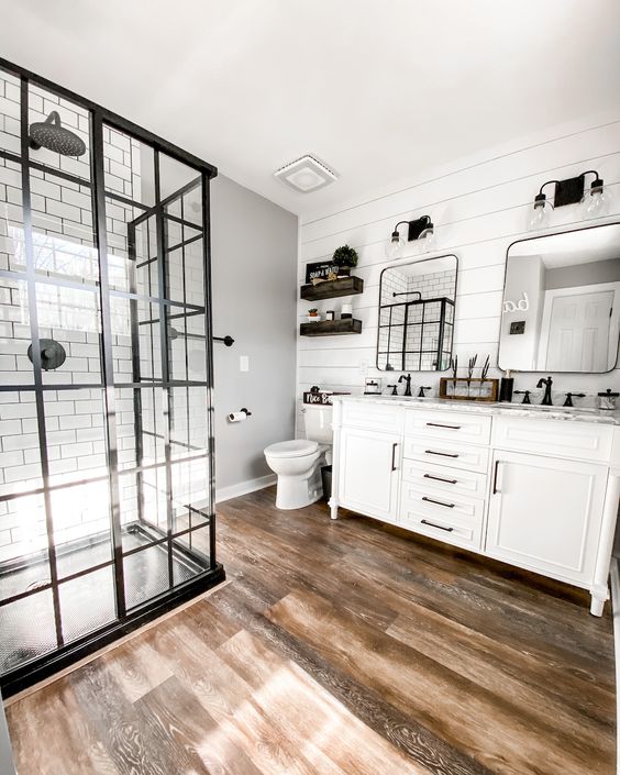 a modern farmhouse bathroom with shiplap walls and white subway tiles, a shower space, a white vanity, mirrors and shelves