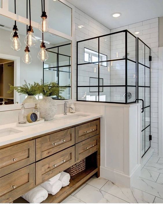 a modern farmhouse bathroom with subway tiles, a shower space, a timber vanity, pendant bulb lamps and a large mirror