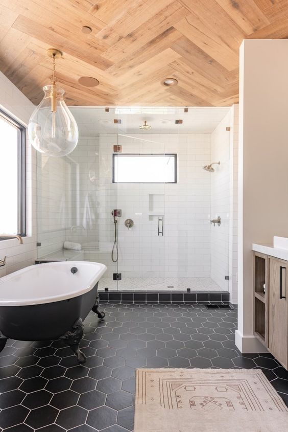 a modern farmhouse bathroom with white and black tiles of different shapes, a timber vanity, a wooden floor, a catchy pendant lamp