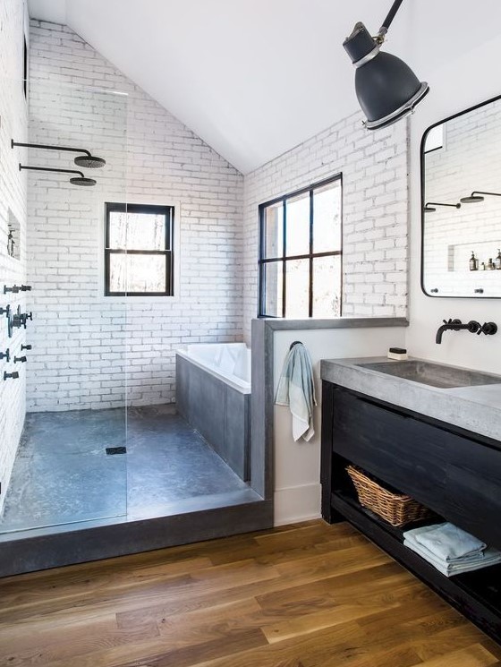 a modern farmhouse bathroom with white tiles, wooden floors, a dark vanity and some concrete