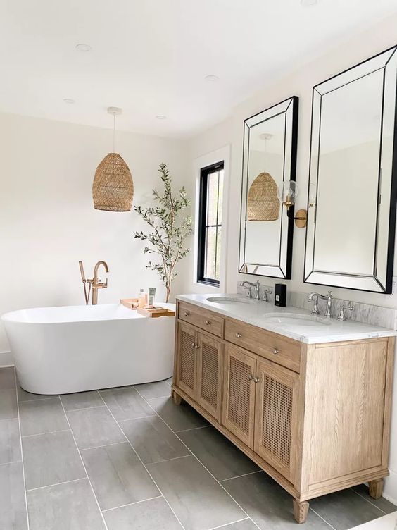 a modern farmhouse bathroom with windows, an oval tub, a stained vanity, mirrors and a woven pendant lamp, a tree in a pot