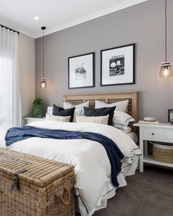 a modern farmhouse bedroom with a grey accent wall, a bed with a stained headboard, white nightstands and a woven basket chest