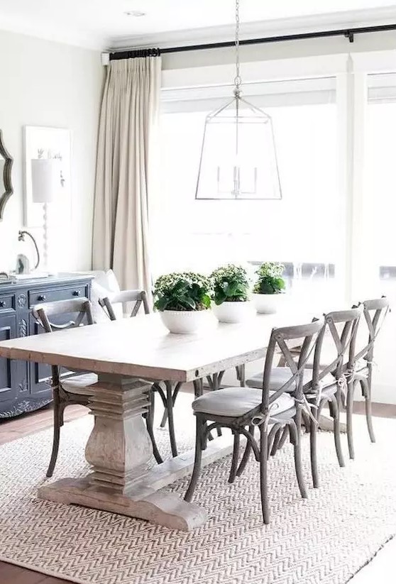 a modern farmhouse dining room with a whitewashed table, white chairs, a frame lamp and a buffet