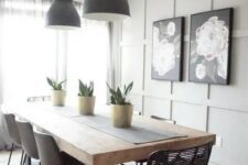 a modern farmhouse dining space with a grey paneled accent wall, a dining table with a thick tabletop, mismatching chairs and blakc pendant lamps