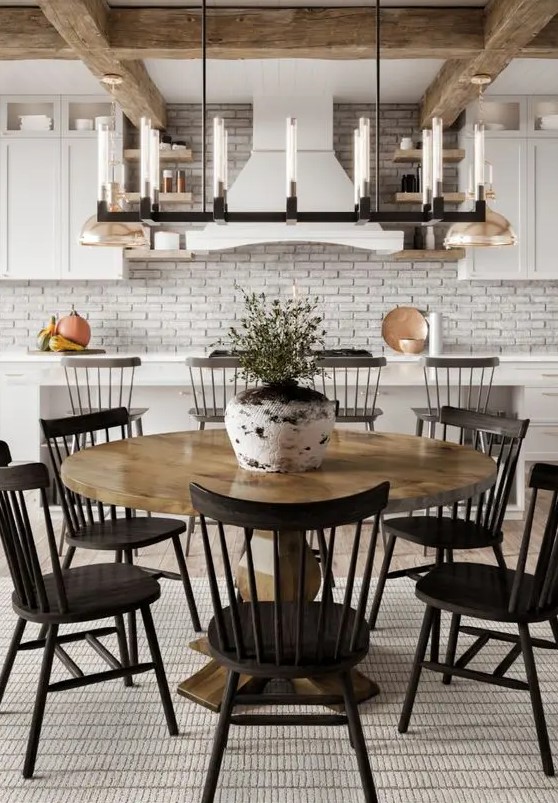 a modern farmhouse dining space with a vintage stained dining table, black chairs, a metal chandelier and greenery