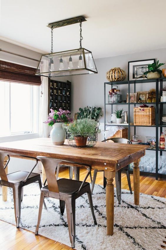 a modern farmhouse dining space with open shelving, a stained vintage table, metal chairs, a pendant lamp and some decor