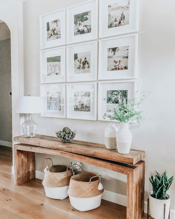 a modern farmhouse entry with a grid gallery wall, a stained bench and baskets, some lovely vases with greenery