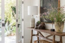 a modern farmhouse entry with a stained console, a basket, a table lamp, some art and blooms is gorgeous