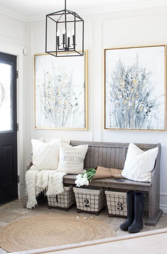 a modern farmhouse entryway with a weathered wood bench, wire baskets for storage, neutral pillows and artworks