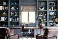 a modern farmhouse home office with grey storage units, a large desk, brown chairs, some plants and some decor