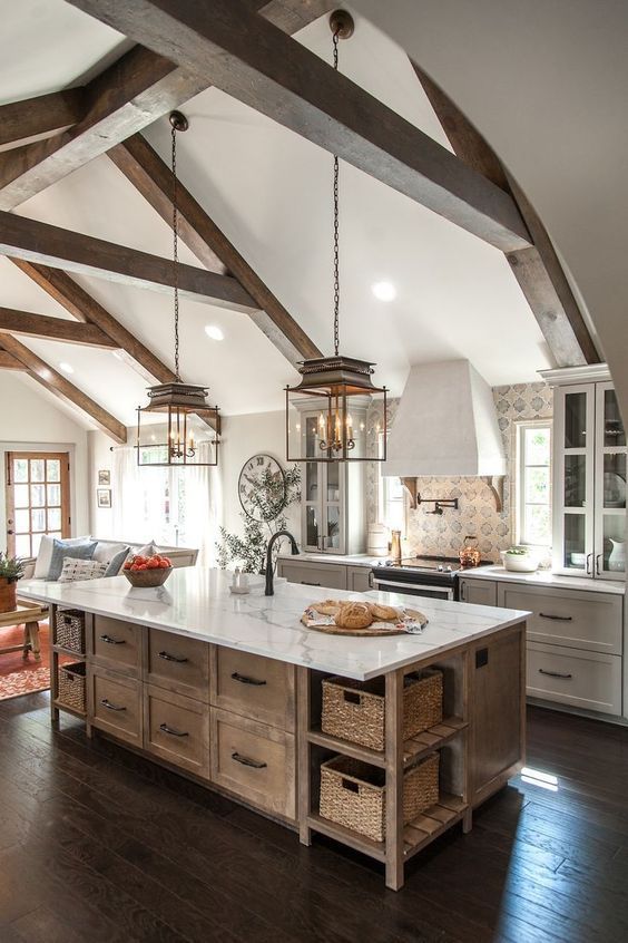 a modern farmhouse kitchen with white shaker style cabinets and a stained kitchen island, a printed tile backsplash and chic pendant lamps