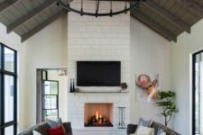 a modern farmhouse living room with a fireplace clad with stone, grey sofas, a coffee table, rug and some decor is cool